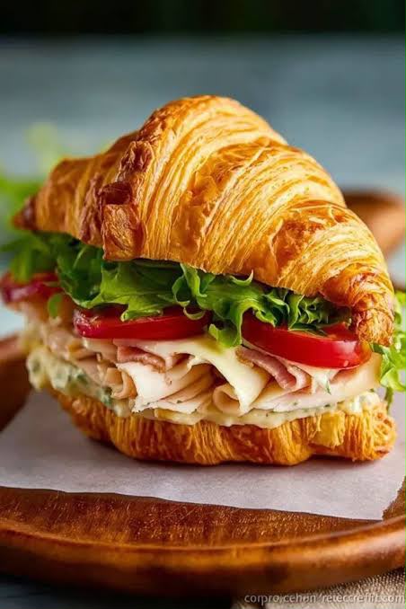 Croissant sandwich with ham, cheese, lettuce and tomato